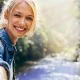 Lächelnde Frau in der Natur mit Bach im Hintergrund