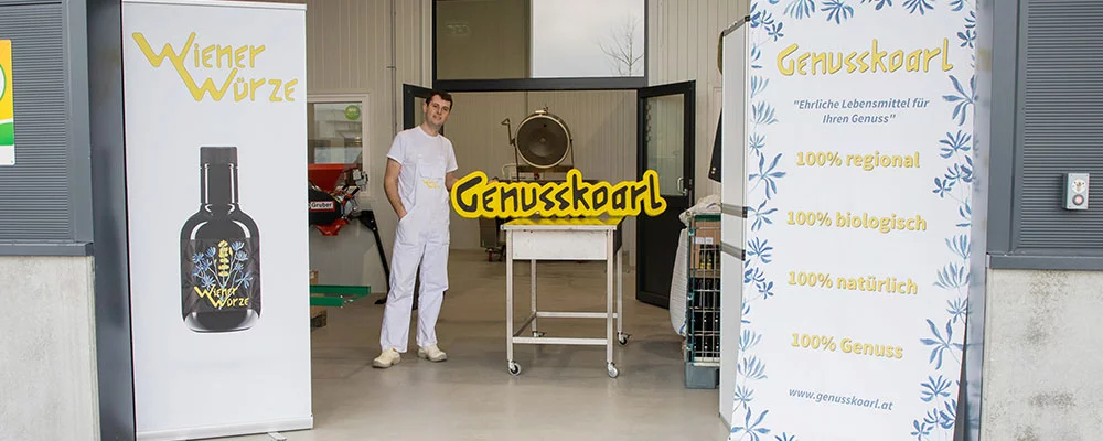 Mitarbeiter von Genusskoarl neben Firmenlogo in Betriebshalle